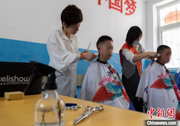 理发师田婕(左)正在和员工为残障儿童剪头发。　杨迪 摄